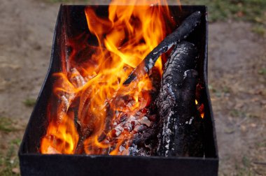 Yanan kırmızı kıvılcımlar ateşten uçar. Işıl ışıl yanan kömür ve yakacak odunları olan ızgara ızgarası.