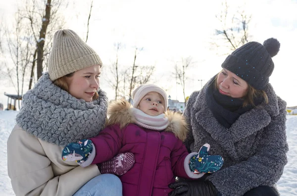 Grandmother, mother and daughter are walking in the winter city park on Christmas and New Year holidays. Parent and little child having fun outdoors