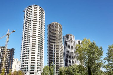 Kule vinci bir ev inşa ediyor. Gökyüzüne karşı inşaat halindeki beton binalar. İnşaat alanı