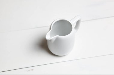 Tahta arka planda boş süt sürahisi. Porselen sos gemisi, sürahi, krema ya da seramik sos kabı.