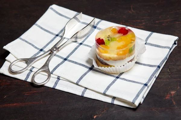 Cake with jelly, kiwi, cherries and mango on table. Yummy mini dessert on a wooden background, closeup