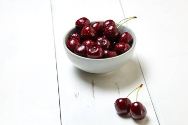 Ahşap arka planda seramik bir kasede tatlı kirazlar, yakın plan. Taze taze kirazlar bir kase içinde su damlacıkları