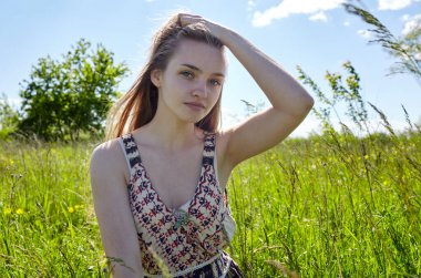 Yaz tarlasında poz veren güzel bir model. Güneşli bir yaz gününde giyinmiş çekici bir genç kızın portresi.