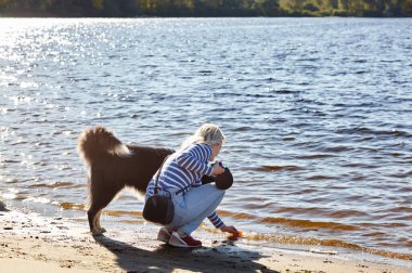 Sahibi sahilde Sibiryalı bir laika köpeğiyle oynuyor. Bir köpekle bir kadının arkadaşlığı.