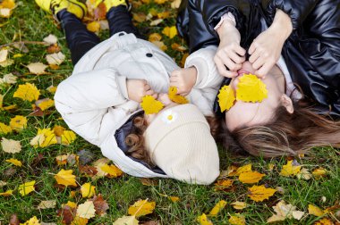 Merhaba Ekim. Anne ve kızı sonbahar şehir parkında yürüyorlar. Ebeveyn ve küçük çocuk dışarıda eğleniyor.