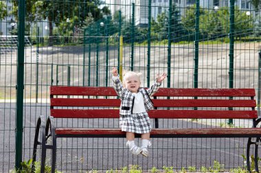 Üzgün küçük kız bankta oturuyor ve annesini bekliyor. Şehir parkında çocuk kaybı