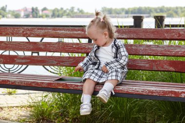 Tarz sahibi küçük bir kız bankta oturuyor ve bir kitaba bakıyor. Şehir parkında çocuk istirahati