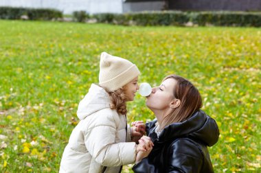 Merhaba Ekim. Anne ve kızı sonbahar şehir parkında yürüyorlar. Ebeveyn ve küçük çocuk dışarıda eğleniyor.