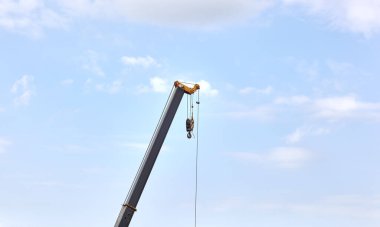 Mavi arka planda yüzen bir kargo vincinin ayrıntıları. İnşaat, ulaşım, ereksiyon vb gibi birçok sektörde ağır kaldırma ve nesneleri hareket ettirmek için kullanılan taşınabilir vinç parçası