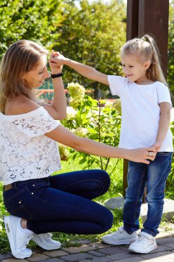 Anne ve kızı yazın şehir parkında yürürler. Çocukluk, eğlence ve insan konsepti - mutlu aile doğada dinlenir ve iyi vakit geçirir.