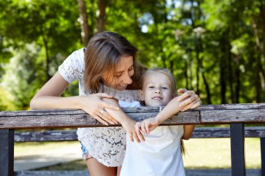 Anne ve kızı yazın şehir parkında yürürler. Çocukluk, eğlence ve insan konsepti - mutlu aile doğada dinlenir ve iyi vakit geçirir.