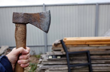 Elinde balta tutan adam. Balta elinde. Güçlü bir adam elinde baltayla yakacak odunların arkasını tutuyor. Seçici odak, bulanık arkaplan