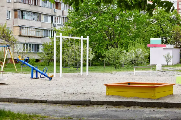 Bahçede çocuksuz renkli bir oyun alanı. Oyun sahası, kum havuzu, salıncak ve diğer oyun alanları. Kentsel mahalle çocukluk kavramı