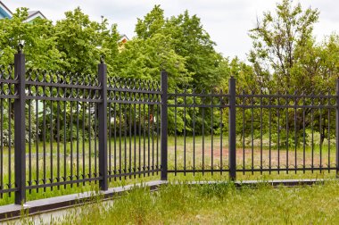 Şehir parkında metal çitler. Korunmak için dekoratif siyah demir parmaklıklar, kapatın.