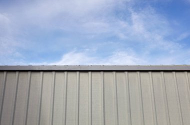 Mavi gökyüzüne karşı yontulmuş çelik çit. Oluklu metal doku yüzeyi veya çeliği galvanize et