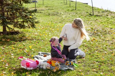 Merhaba Ekim. Anne ve kızı sonbahar şehir parkında yürüyorlar. Ebeveyn ve küçük çocuk dışarıda eğleniyor.