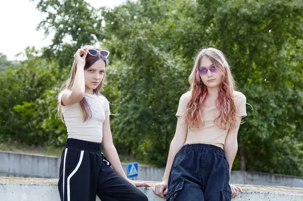 Sokakta duran güneş gözlüklü iki genç kız arkadaş. Moda kıyafetleri içinde hippi kızlar. Mutlu kız arkadaşlar rahatlıyor ve iyi vakit geçiriyor.
