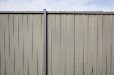 Mavi gökyüzüne karşı yontulmuş çelik çit. Oluklu metal doku yüzeyi veya çeliği galvanize et