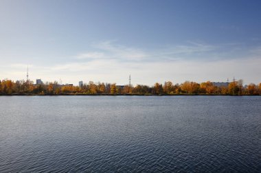 Güzel Avrupa sonbaharı şehir manzarası. Avrupa 'nın başkenti Kyiv' de nehir kenarındaki sık ağaçlarla mavi gökyüzü manzarası