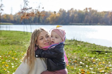Merhaba Ekim. Anne ve kızı sonbahar şehir parkında yürüyorlar. Ebeveyn ve küçük çocuk dışarıda eğleniyor.