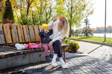 Merhaba Ekim. Anne ve kızı sonbahar şehir parkında yürüyorlar. Ebeveyn ve küçük çocuk dışarıda eğleniyor.