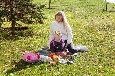 Merhaba Ekim. Anne ve kızı sonbahar şehir parkında yürüyorlar. Ebeveyn ve küçük çocuk dışarıda eğleniyor.