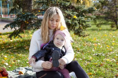 Merhaba Ekim. Anne ve kızı sonbahar şehir parkında yürüyorlar. Ebeveyn ve küçük çocuk dışarıda eğleniyor.