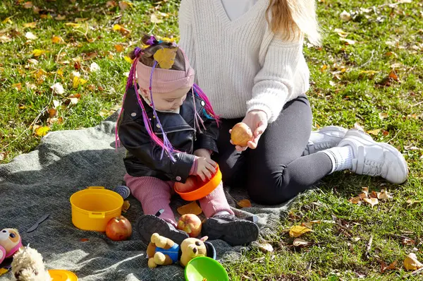 Merhaba Ekim. Anne ve kızı sonbahar şehir parkında yürüyorlar. Ebeveyn ve küçük çocuk dışarıda eğleniyor.