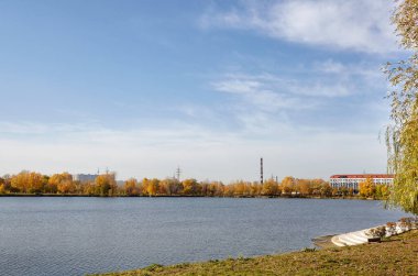 Güzel Avrupa sonbaharı şehir manzarası. Avrupa 'nın başkenti Kyiv' de nehir kenarındaki sık ağaçlarla mavi gökyüzü manzarası