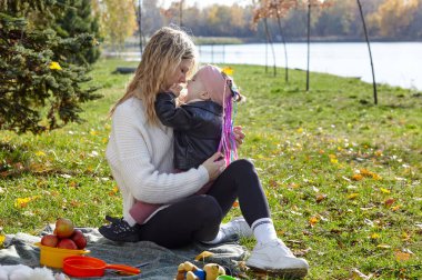 Merhaba Ekim. Anne ve kızı sonbahar şehir parkında yürüyorlar. Ebeveyn ve küçük çocuk dışarıda eğleniyor.