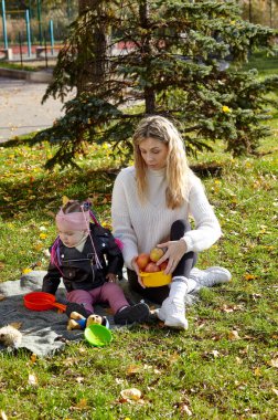 Merhaba Ekim. Anne ve kızı sonbahar şehir parkında yürüyorlar. Ebeveyn ve küçük çocuk dışarıda eğleniyor.
