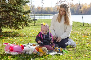 Merhaba Ekim. Anne ve kızı sonbahar şehir parkında yürüyorlar. Ebeveyn ve küçük çocuk dışarıda eğleniyor.