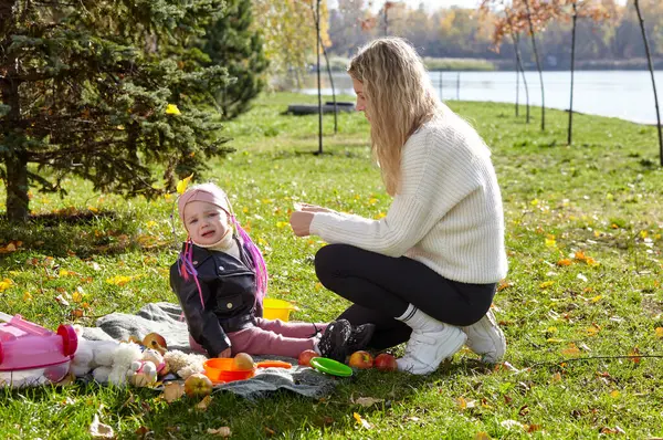 Bebek ağIıyor. Anne ve kızı sonbahar parkında ekose giymişler. Üzgün çocuk.