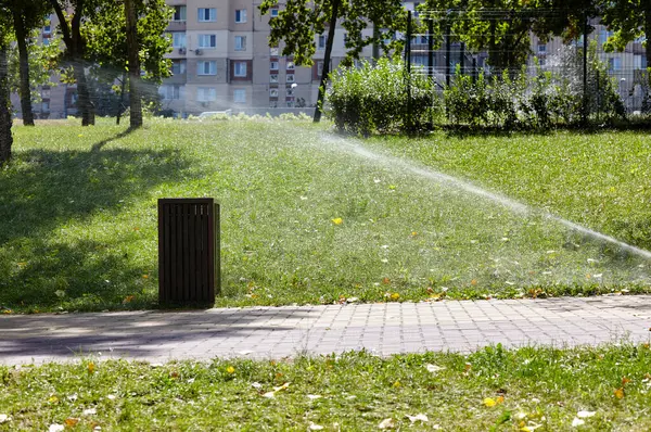 Çimlerin sulanması ve bakımı, sonbahar parkında bahçe bakımı için otomatik ekipman. Bahçe sulama sistemi çimenleri suluyor