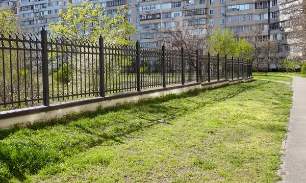 Şehir parkında metal çitler. Korunmak için dekoratif siyah demir parmaklıklar, kapatın.