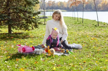 Merhaba Ekim. Anne ve kızı sonbahar şehir parkında yürüyorlar. Ebeveyn ve küçük çocuk dışarıda eğleniyor.