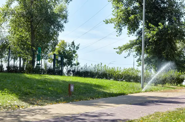 Çimlerin sulanması ve bakımı, sonbahar parkında bahçe bakımı için otomatik ekipman. Bahçe sulama sistemi çimenleri suluyor