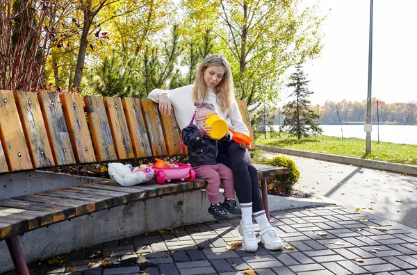 Merhaba Ekim. Anne ve kızı sonbahar şehir parkında yürüyorlar. Ebeveyn ve küçük çocuk dışarıda eğleniyor.