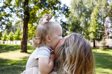 Anne ve kızı yazın şehir parkında yürürler. Çocukluk, eğlence ve insan konsepti - mutlu aile doğada dinlenir ve iyi vakit geçirir.