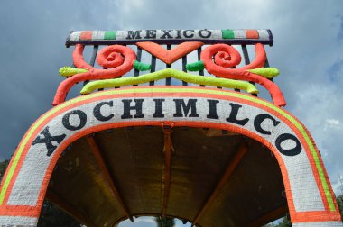 Colorida y conocidas trajineras de Xochimilco, Mxico. Sobre un fondo de nubles nublado y resaltando su nombre