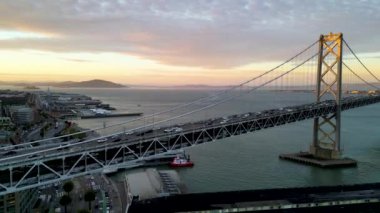 Şehir merkezindeki gökdelenleri keşfetmek için San Francisco Bay Köprüsü 'nün etrafında pembe gün ışığı altında uçan sinemacılar. San Francisco USA, asma köprü simgesi Kaliforniya. Çekim ayarlanıyor