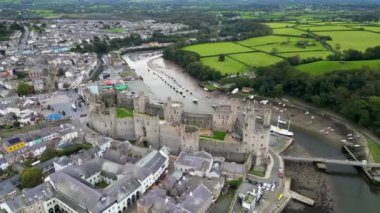 Caernarfon Kalesi, Caernarfon, Gwynedd, Galler, Birleşik Krallık 'ın en iyi sinematik manzarası. Kuzey Galler 'in Caernarfon kasabasının insansız hava aracı görüntüleri. 