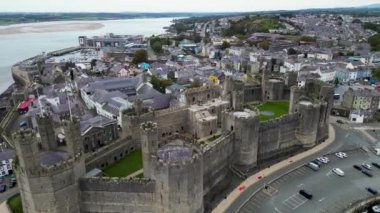 Caernarfon Kalesi, Caernarfon, Gwynedd, Galler, Birleşik Krallık 'ın en iyi sinematik manzarası. Kuzey Galler 'in Caernarfon kasabasının insansız hava aracı görüntüleri. 