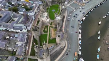 Caernarfon Kalesi, Caernarfon, Gwynedd, Galler, Birleşik Krallık 'ın en iyi sinematik manzarası. Kuzey Galler 'in Caernarfon kasabasının insansız hava aracı görüntüleri. 