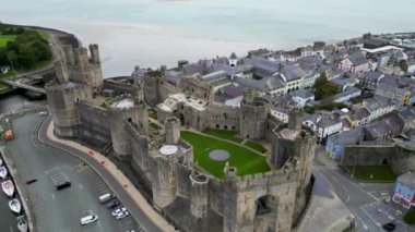 Caernarfon Kalesi, Caernarfon, Gwynedd, Galler, Birleşik Krallık 'ın en iyi sinematik manzarası. Kuzey Galler 'in Caernarfon kasabasının insansız hava aracı görüntüleri. 
