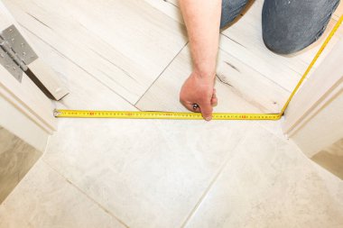 Installation of threshold indoors.  Man with a measuring tape. Renovation works in the flat.