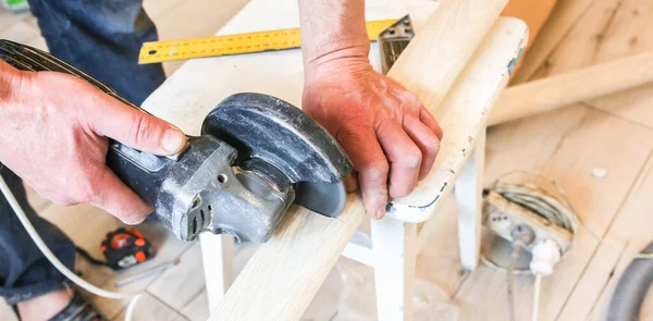 stock image Man is cutting baseboard. Repair works indoors. Renovation in the flat.  Angle grinder in hands.