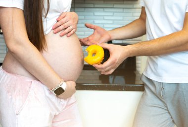 Sweet donut and pregnant woman. Healthy food during pregnancy.