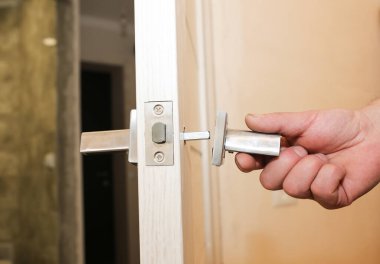 Adam kapı kolunu kuruyor. Onarım işe yarıyor. Dairede bakım var..