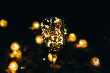 Şarap kadehindeki ışıklar. Kalpler arka planda. Romantik aşk kavramı. Şenlikli fikirler. Sevgililer Günü kartpostalı.